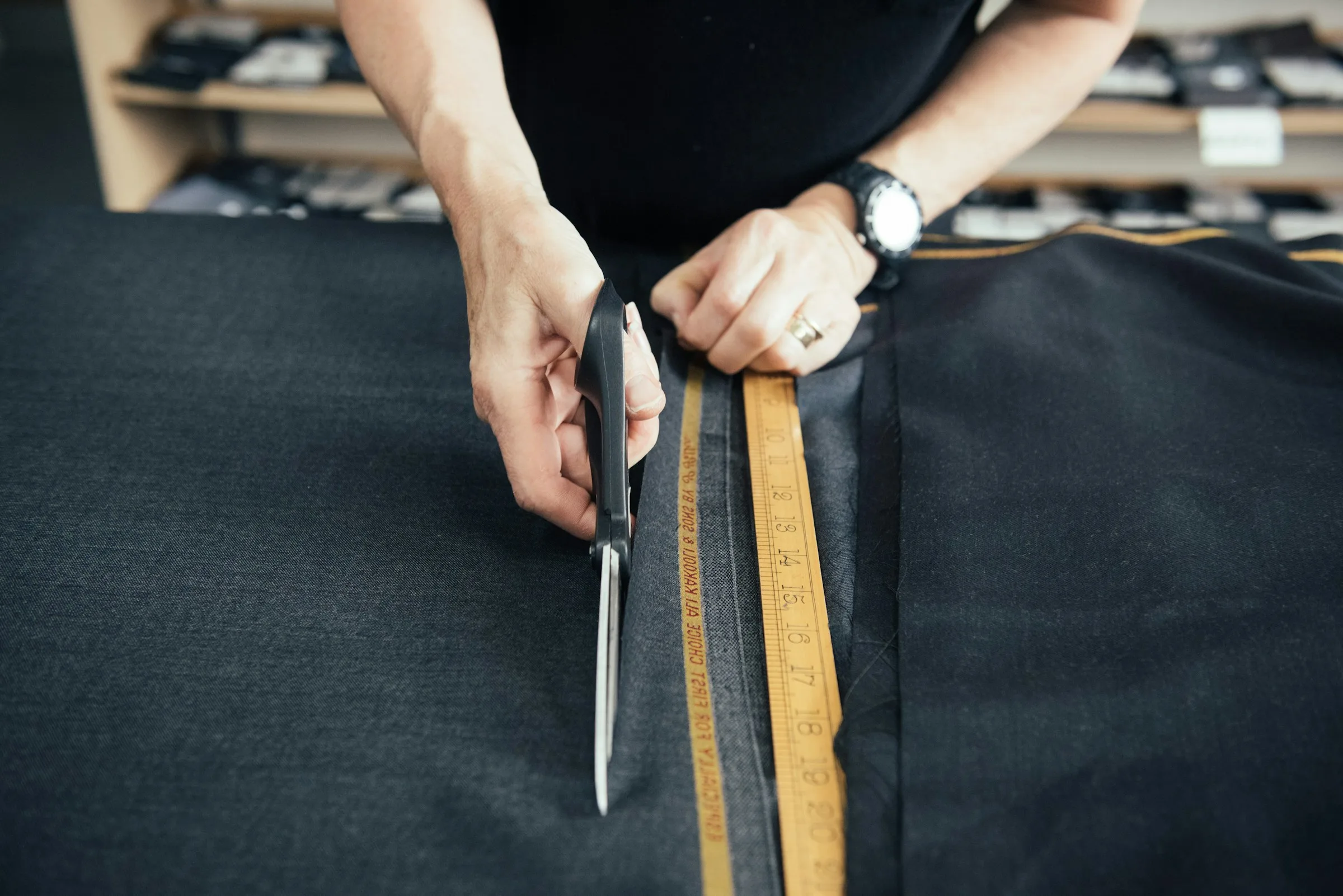 Tailor cutting suit cloth with scissors and measuring tape