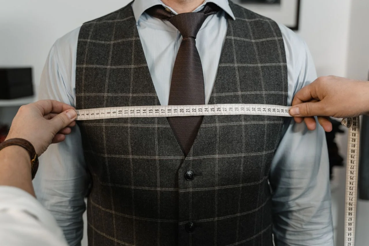 Tailor measuring a client's chest for a bespoke suit fitting